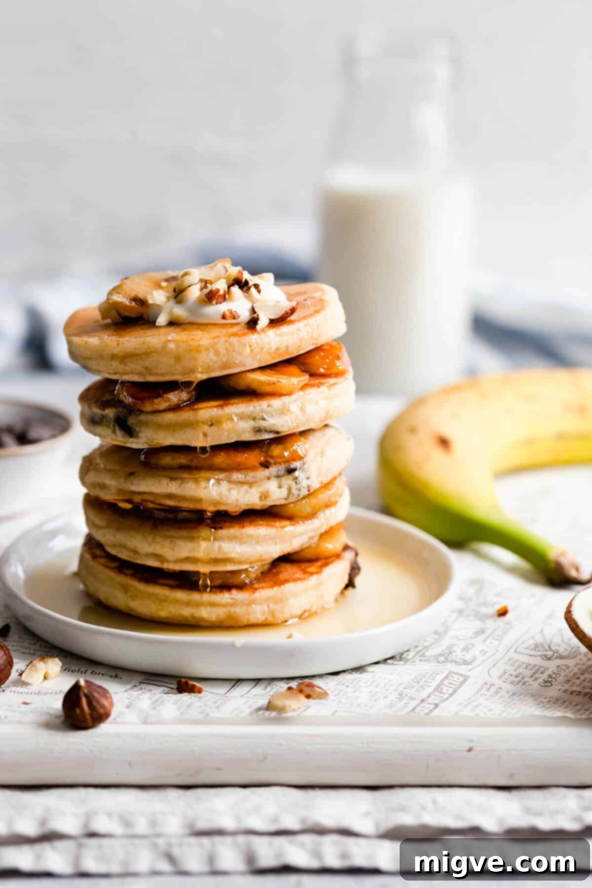 Caramelized Banana Hazelnut Stack 2 Stack of fluffy caramelised banana and hazelnut pancakes drizzled with maple syrup