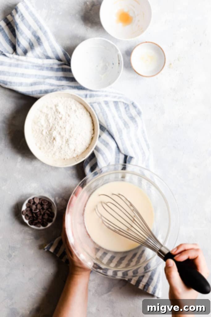 Caramelized Banana Hazelnut Stack 6 Overhead shot of a person mixing pancake batter in a bowl with a whisk