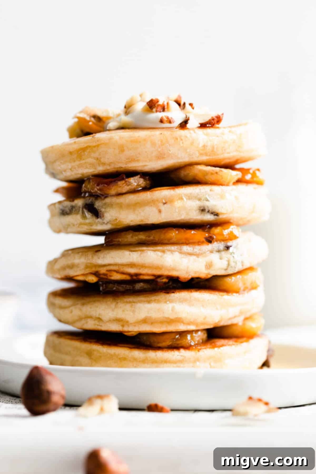 Caramelized Banana Hazelnut Stack 10 Close-up side view of a stack of golden brown pancakes with sticky, sweet caramelised banana slices layered between them