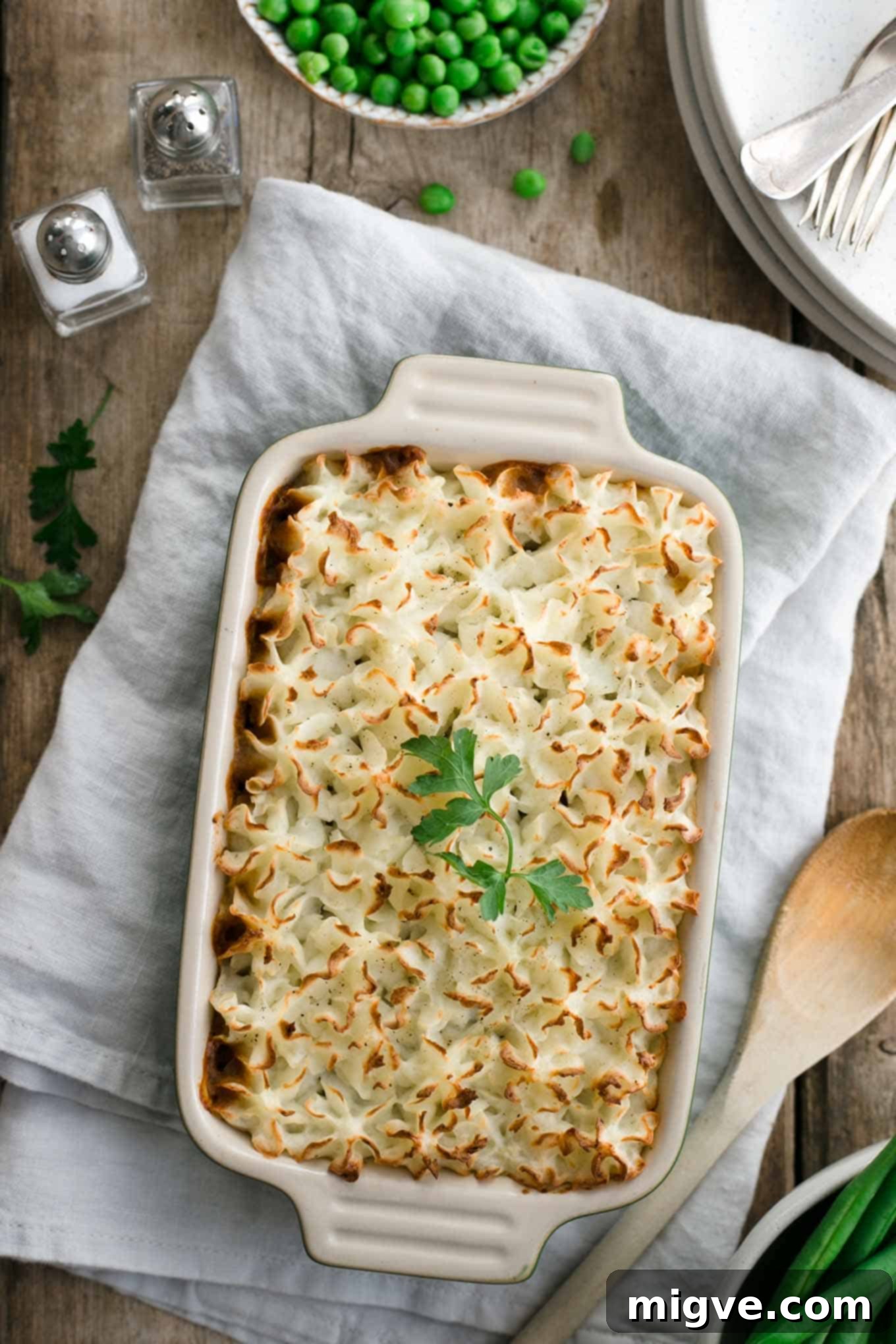 An overhead view of mini lentil shepherd's pies, showcasing the rich, savory filling beneath the perfectly piped mashed potato.