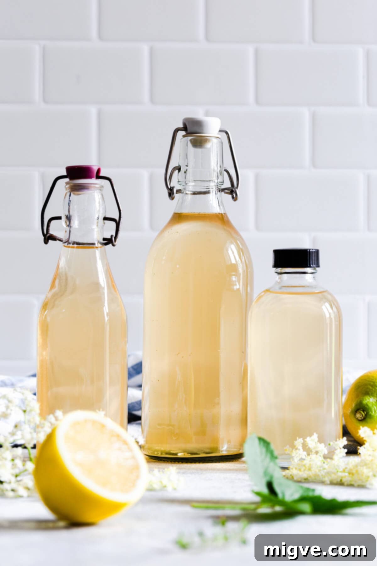 straight ahead view of 3 different glass bottles filled with elderflower cordial