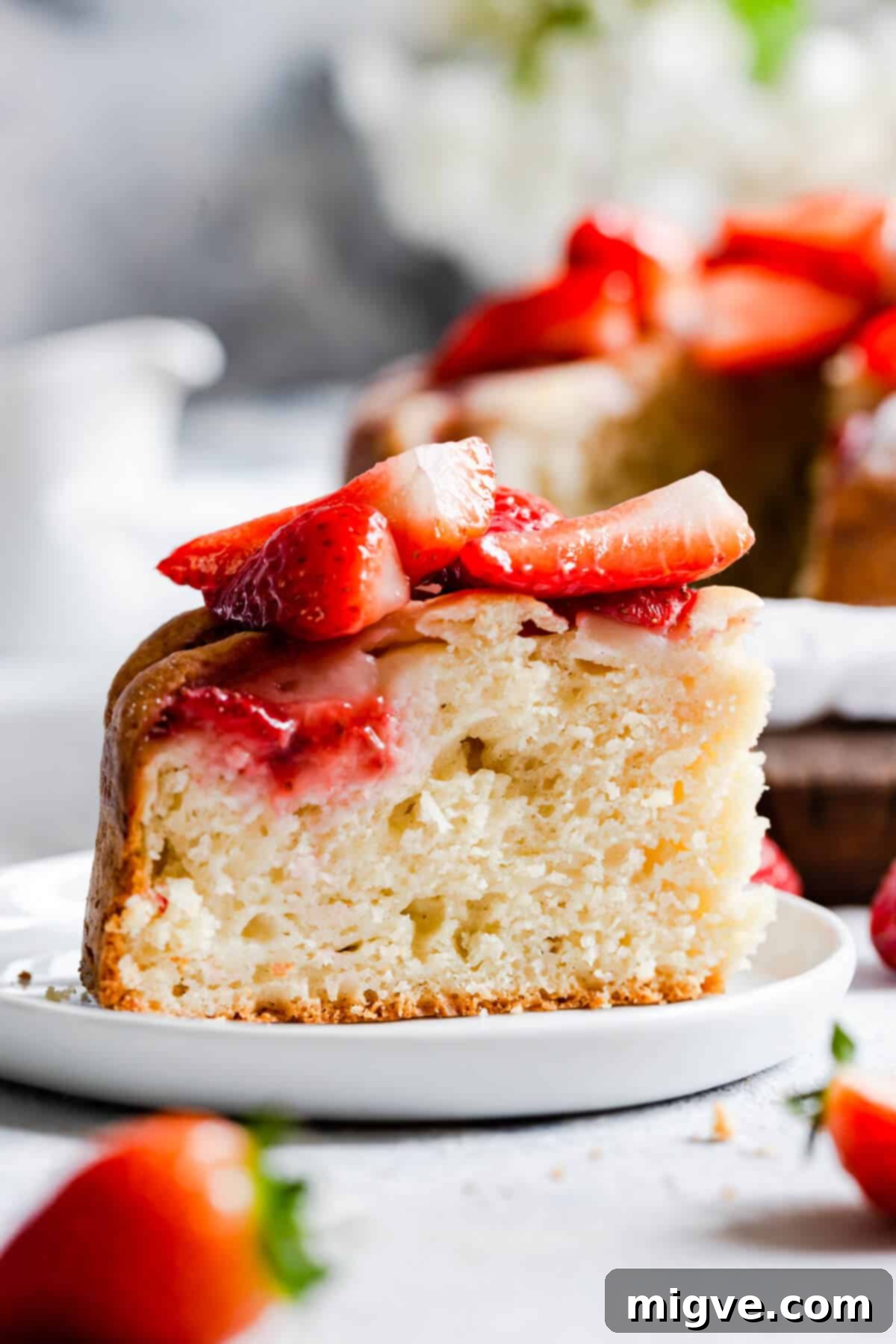 Extreme close-up of a slice of fresh strawberry yogurt cake, showing its light, fluffy texture and embedded strawberry pieces.