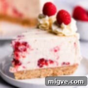 Slice of no bake cheesecake with fresh raspberries and white chocolate.