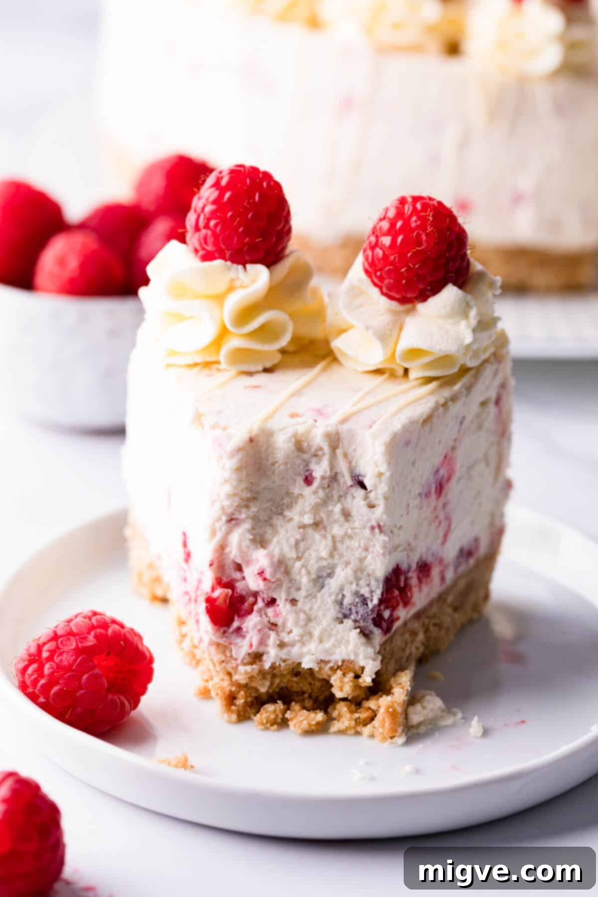 Slice of raspberry cheesecake on a small plate with bite missing.