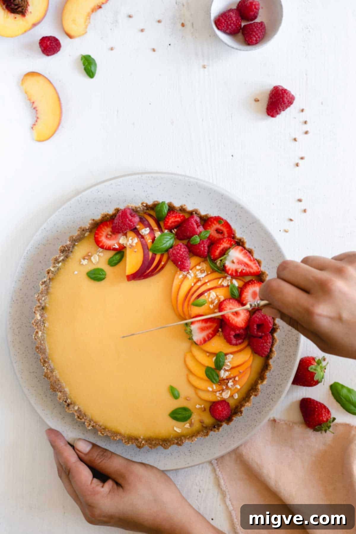 Wholesome Golden Peach Tart 10 Cutting a slice of vegan peach tart topped with fresh summer berries