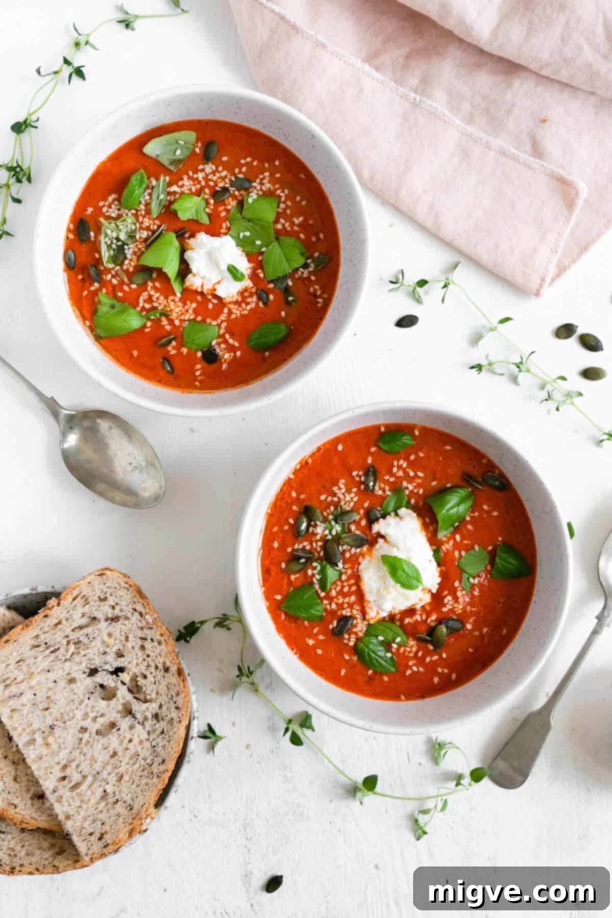 Overhead shot of a bowl of roasted tomato and red pepper soup, garnished with olive oil drizzle