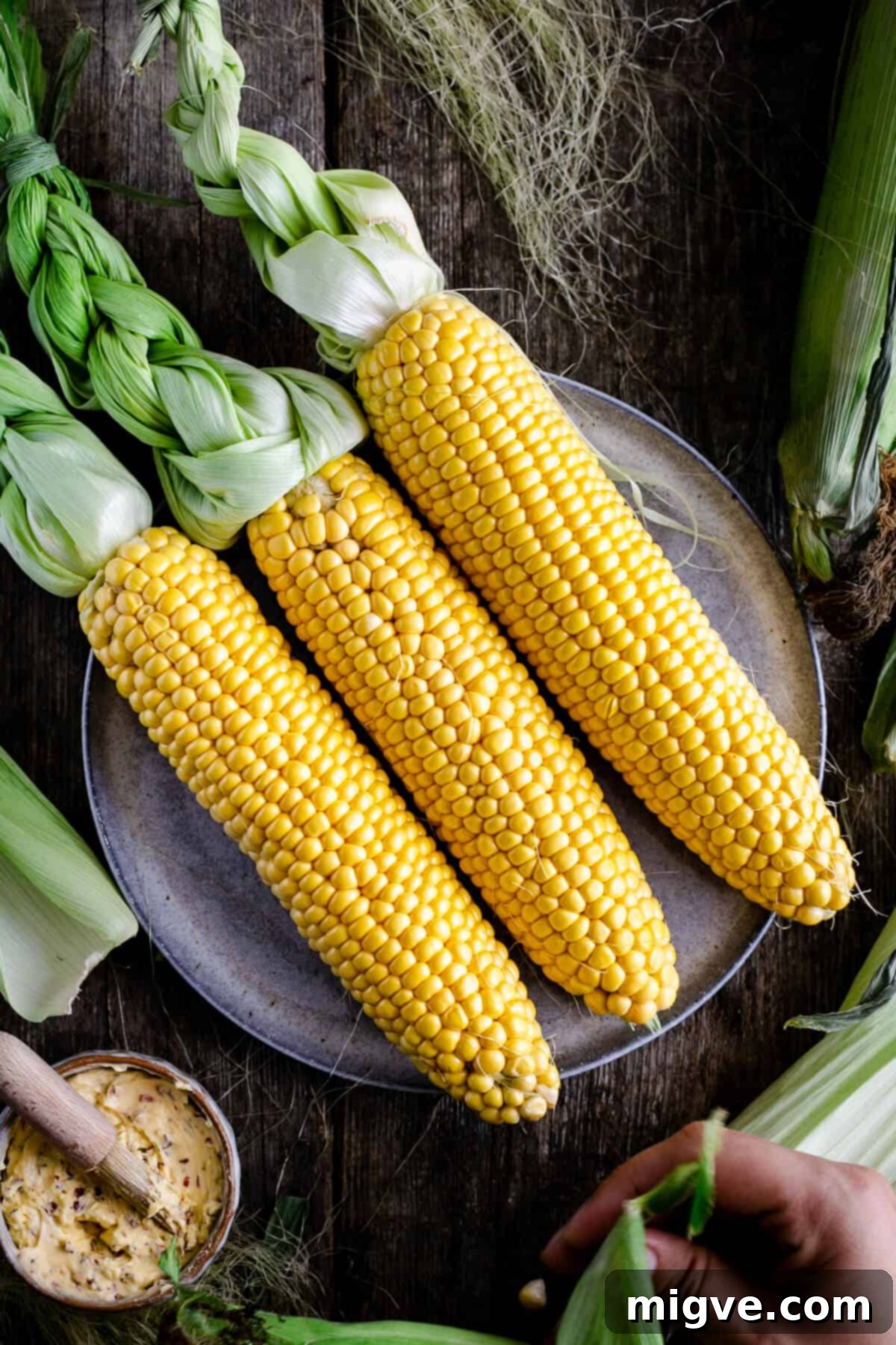 Three fresh cobs of corn on the plate, ready for preparation
