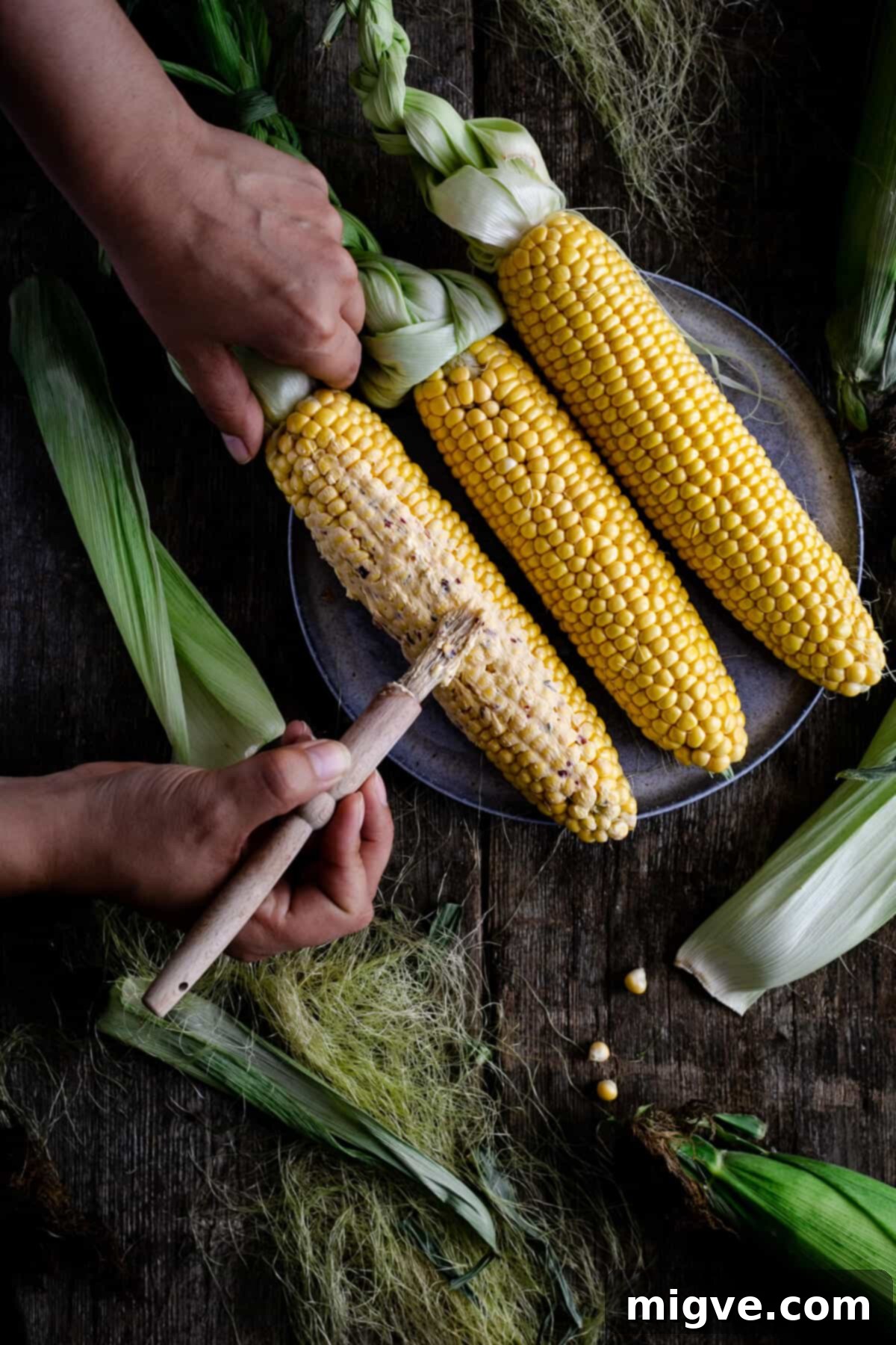 Spreading chilli-infused butter on cobs of corn with a pastry brush before cooking