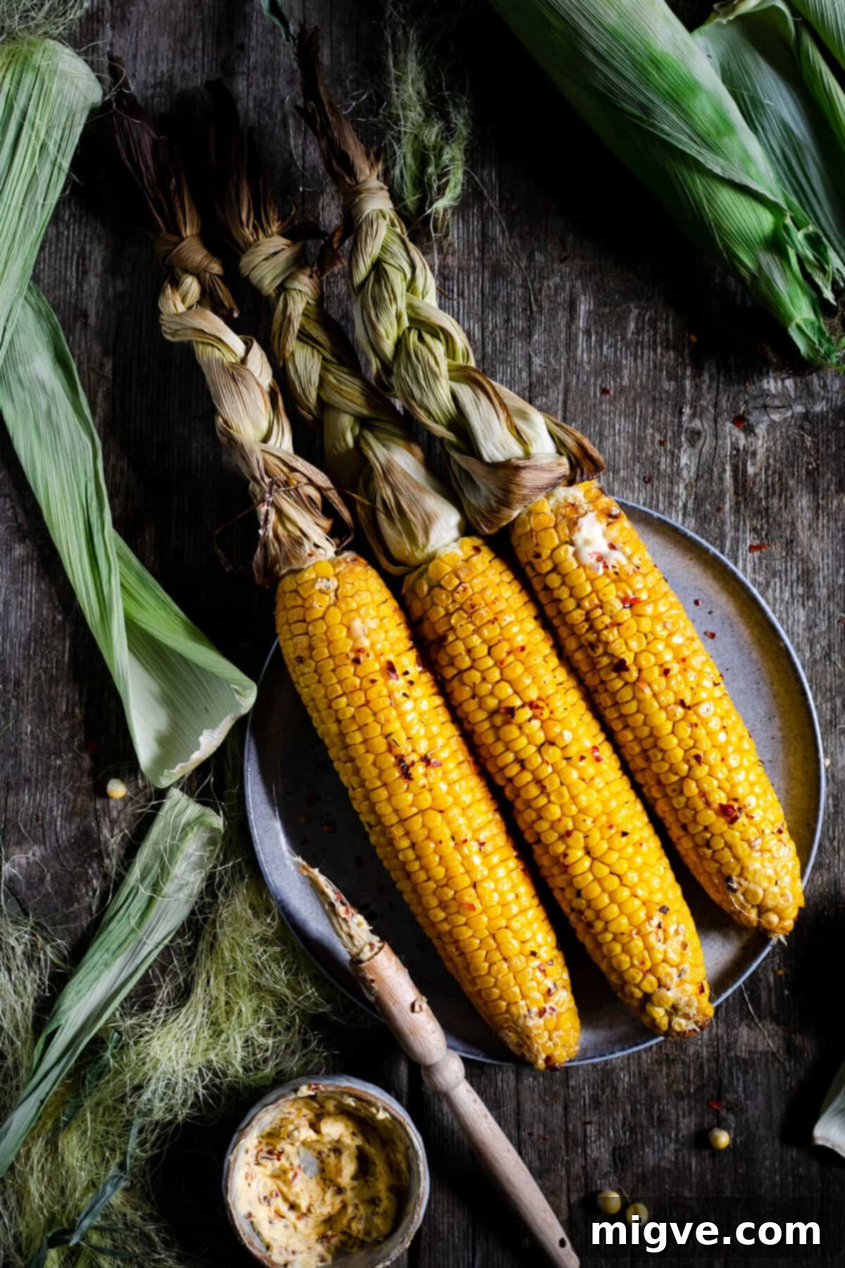 Overhead shot of oven-roasted corn on the cob with chilli butter, garnished and ready to serve