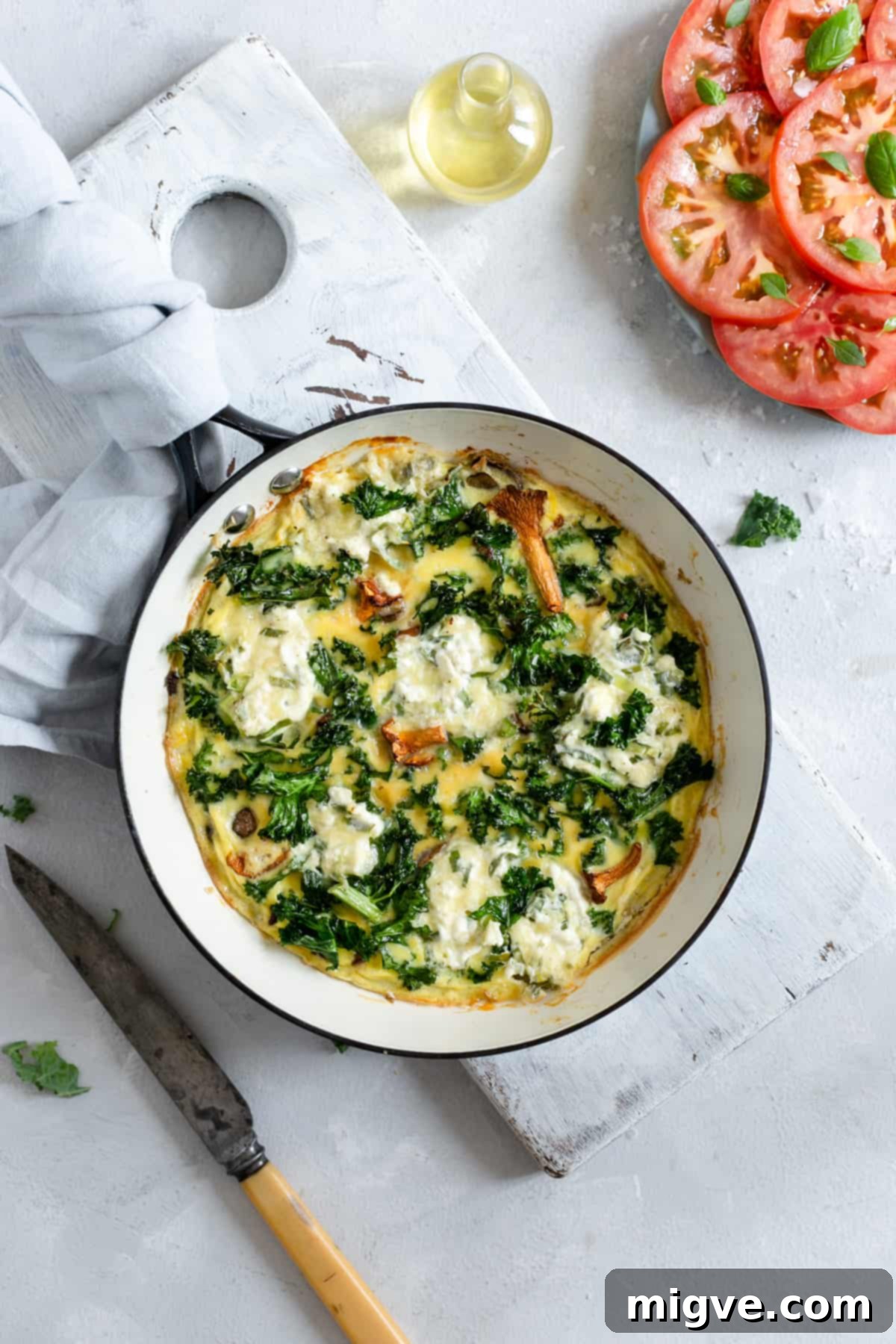 Overhead shot of mushroom and kale frittata with fresh tomato salad, ready to be served.