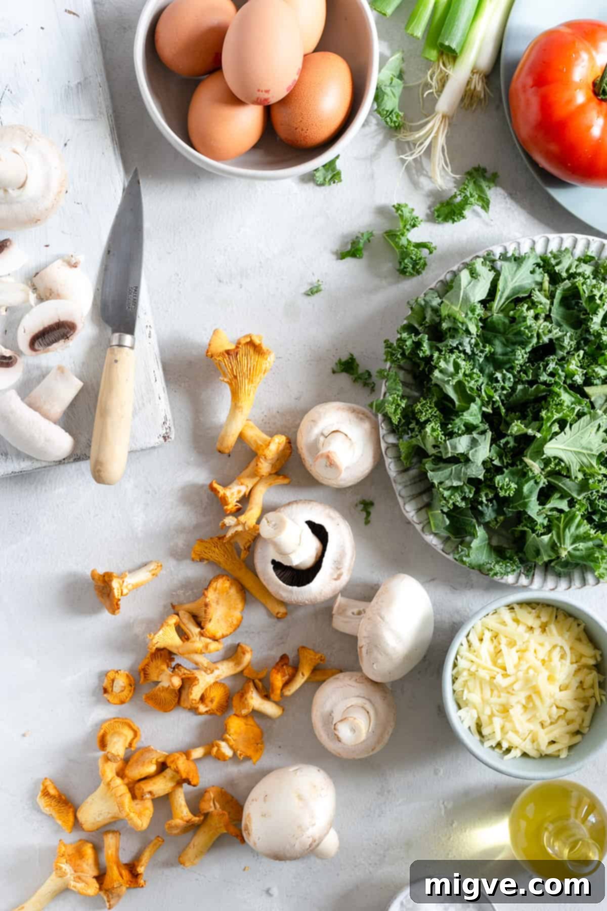 Fresh ingredients for mushroom and kale frittata, including eggs, mushrooms, kale, and cheese.