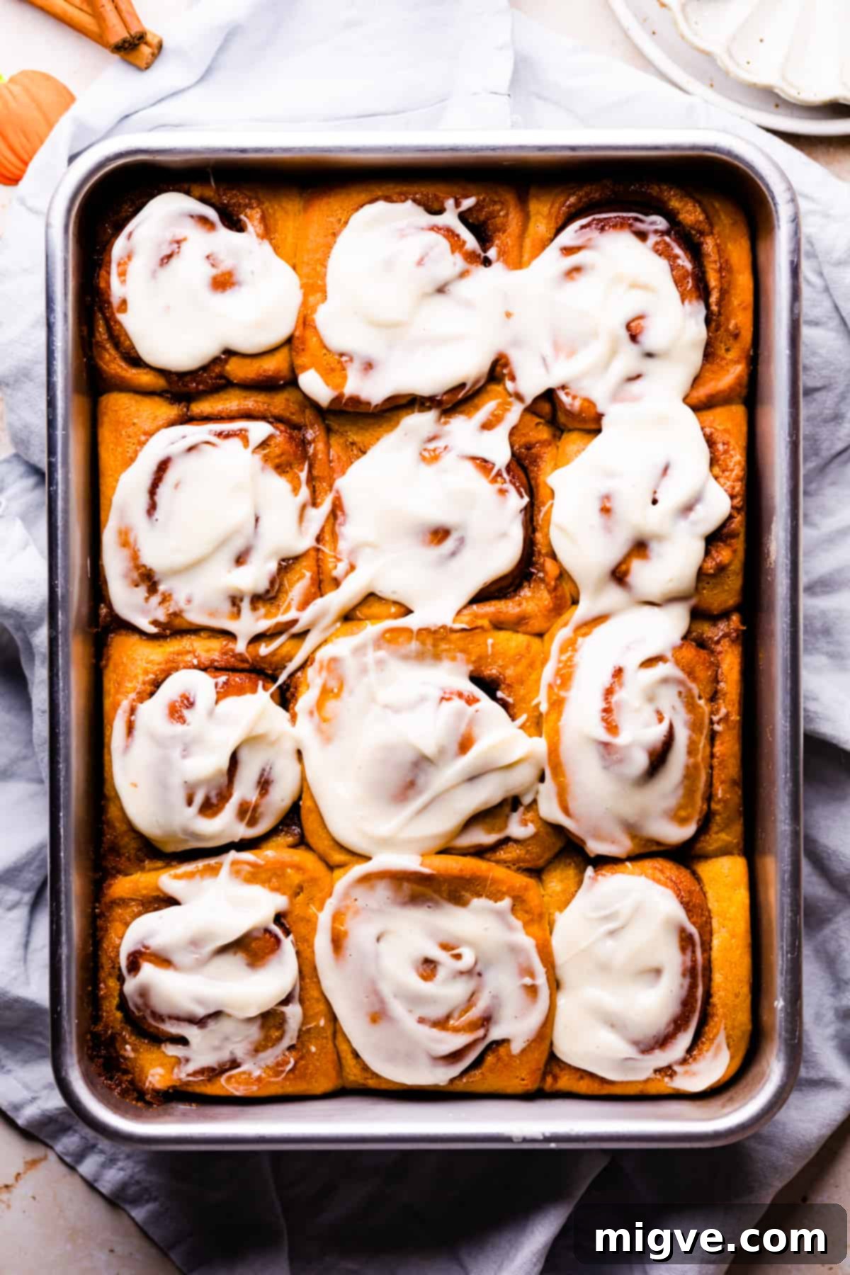 Super soft and fluffy pumpkin cinnamon rolls in a rectangular baking dish topped with cream cheese glaze.