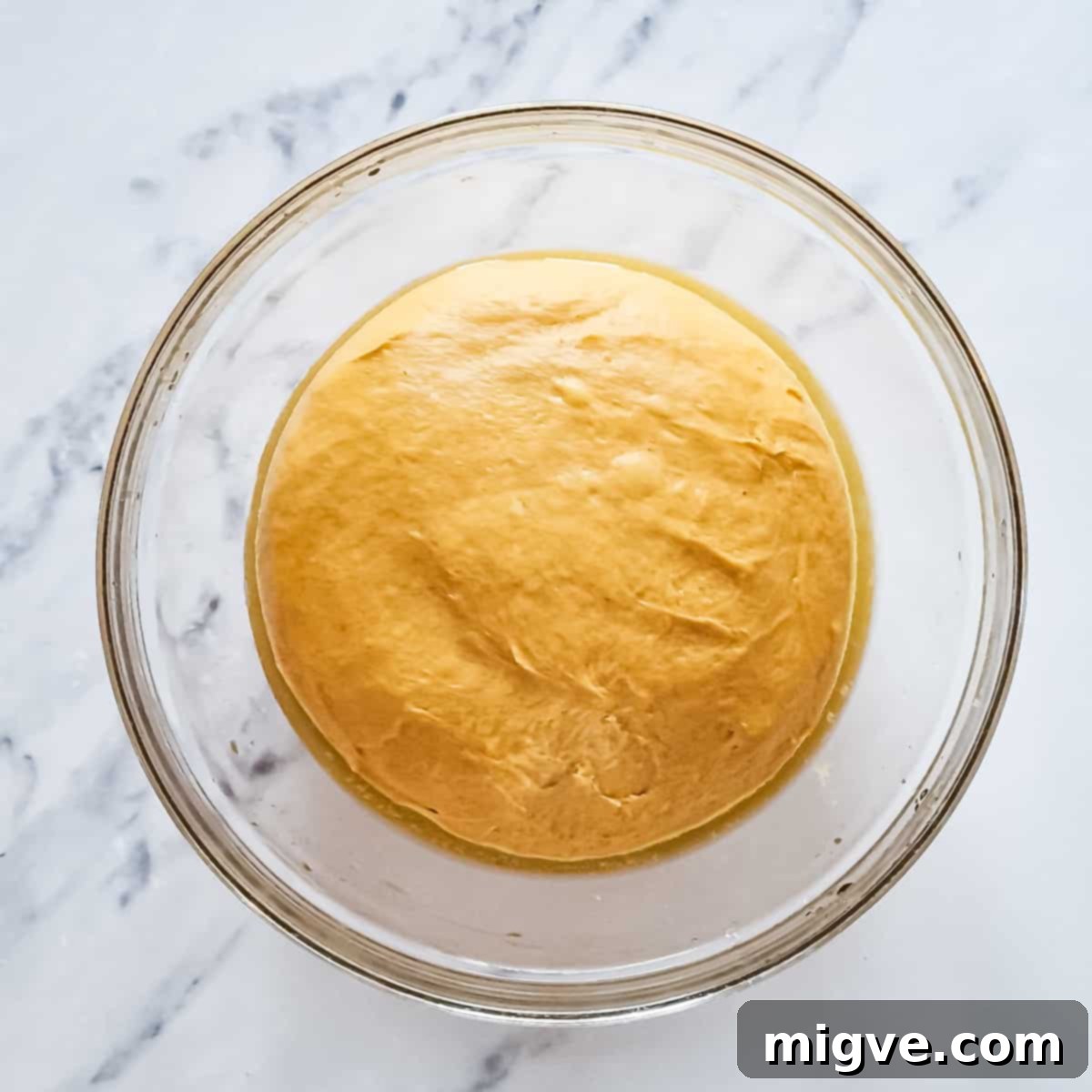 Glass bowl with dough for pumpkin sticky buns after kneading.