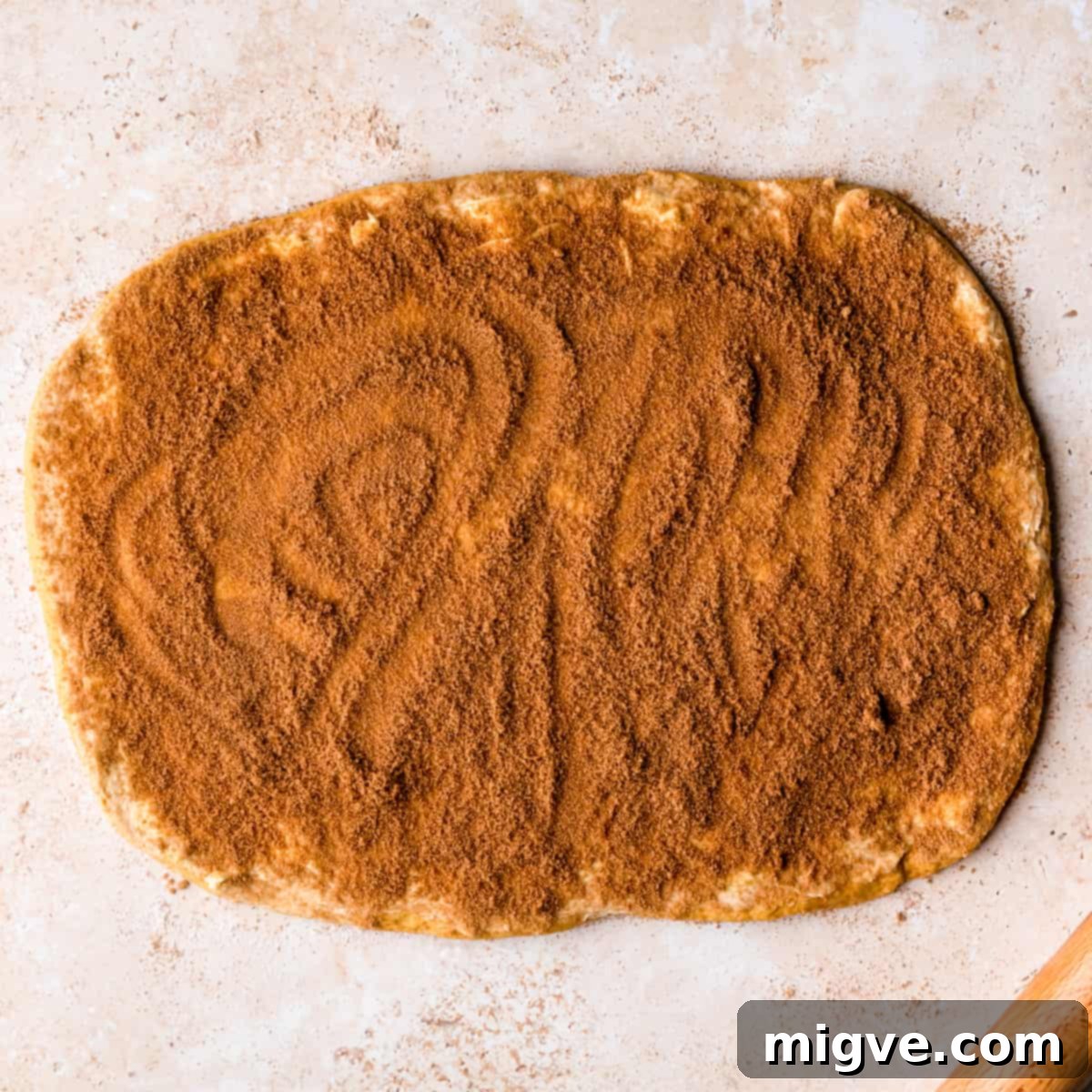 Dough rolled into a rough rectangle topped with softened butter, brown sugar, and cinnamon mixture.