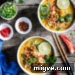 Overhead shot of two bowls of Thai style pumpkin laksa topped with roasted chickpeas and fresh mint