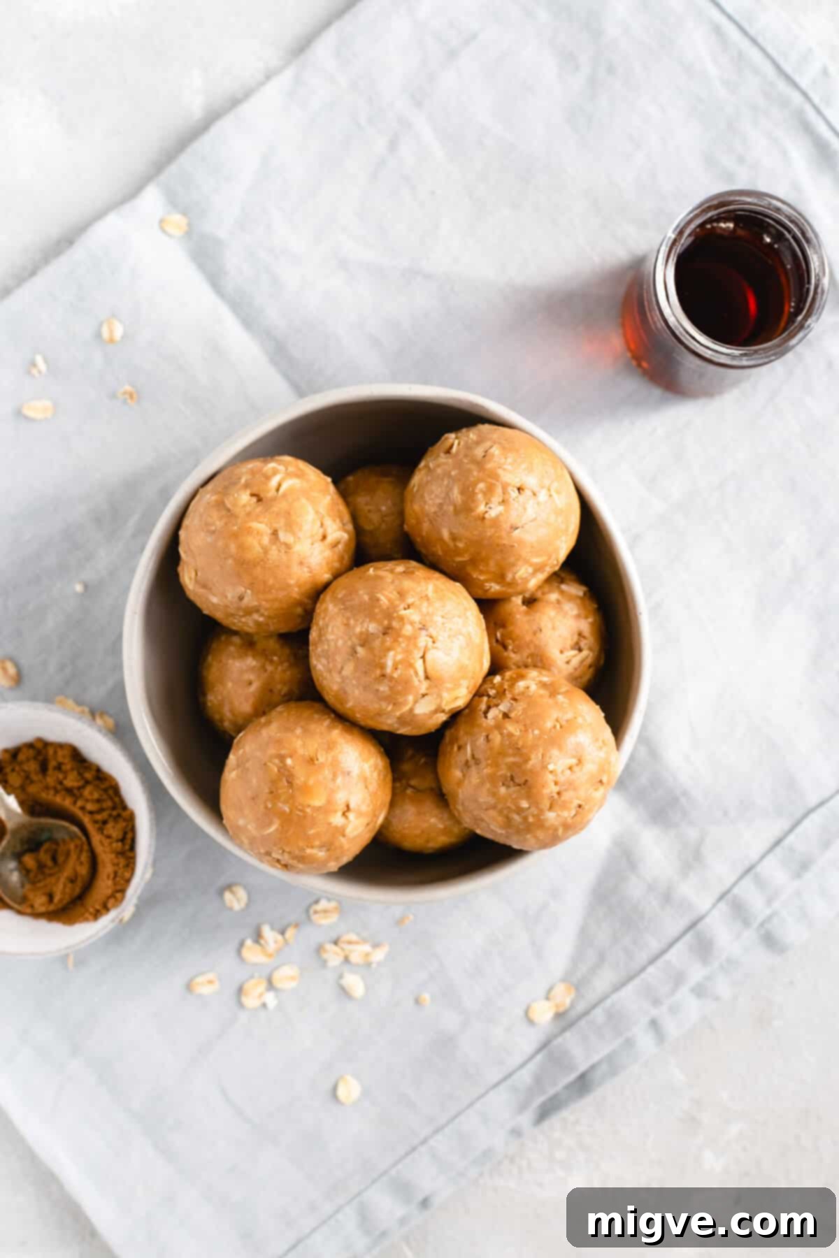 Spiced Coconut Peanut Power Bites 6 Overhead shot of a beautiful bowl filled with delicious coconut and peanut butter spiced energy bites, with maple syrup and mixed spice on the side
