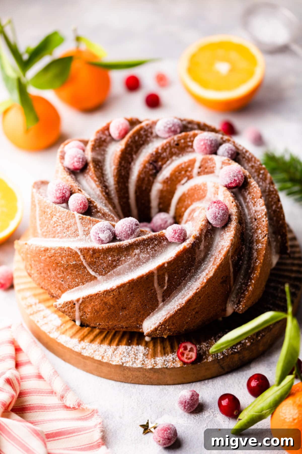 bundt cake on wooden cake board topped with cranberries covered in sugar.