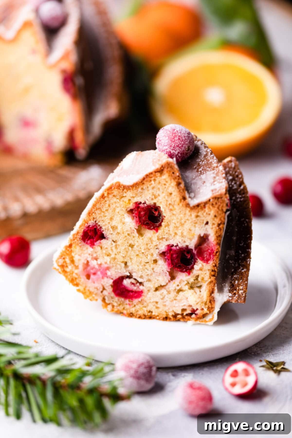 an individual slice of orange and cranberry bundt cake on a small plate.