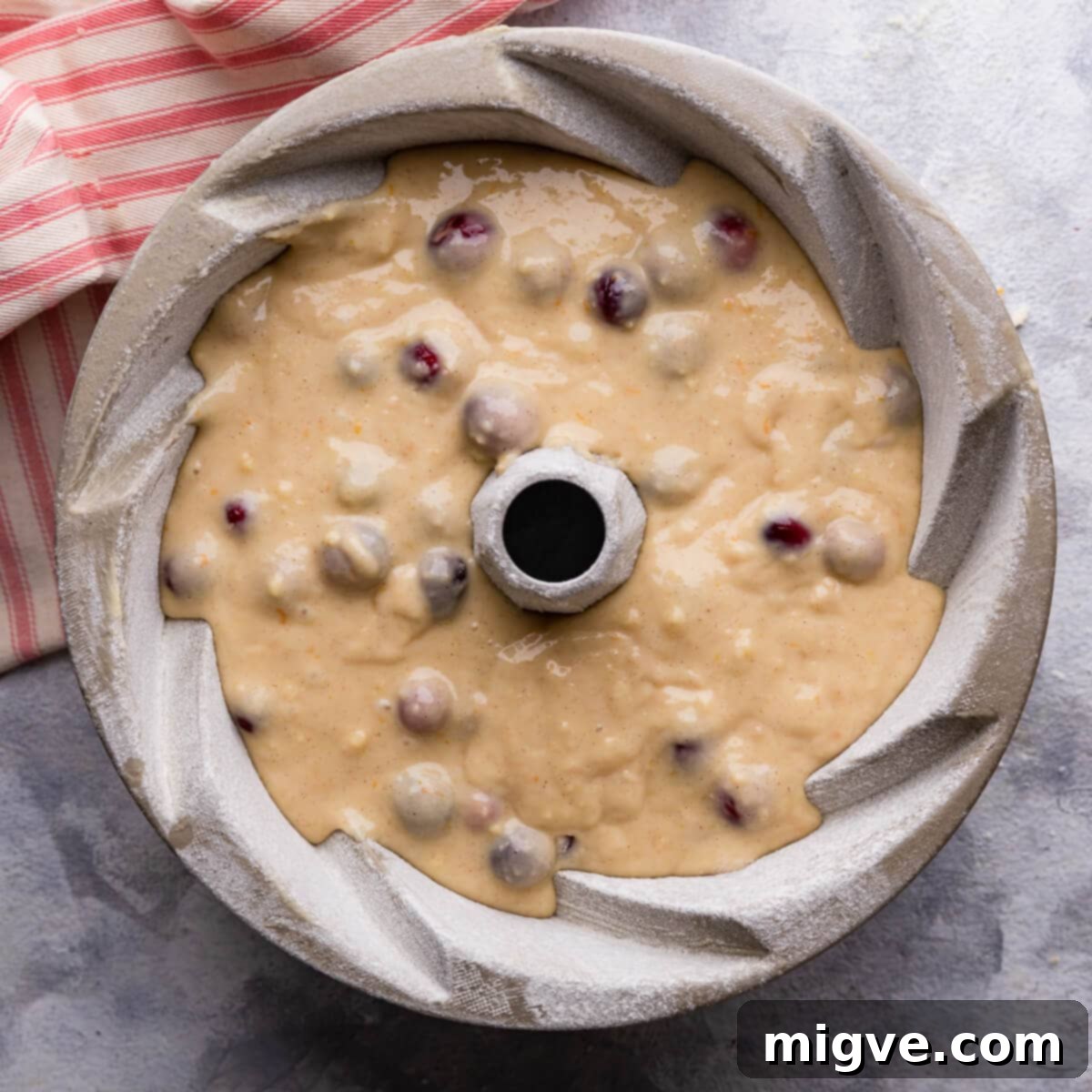 batter for orange cranberry bundt cake inside of the baking tin.