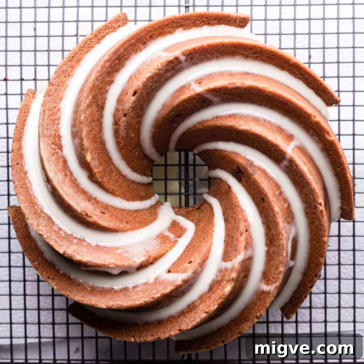 orange cranberry bundt cake drizzled with glaze on a cooling rack.