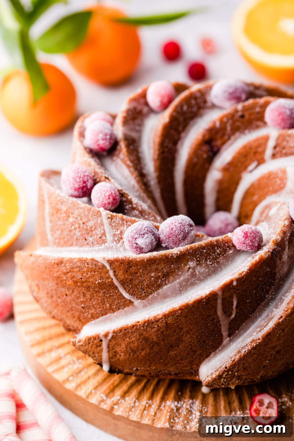 orange cranberry bundt cake topped with glaze and sugared cranberries.