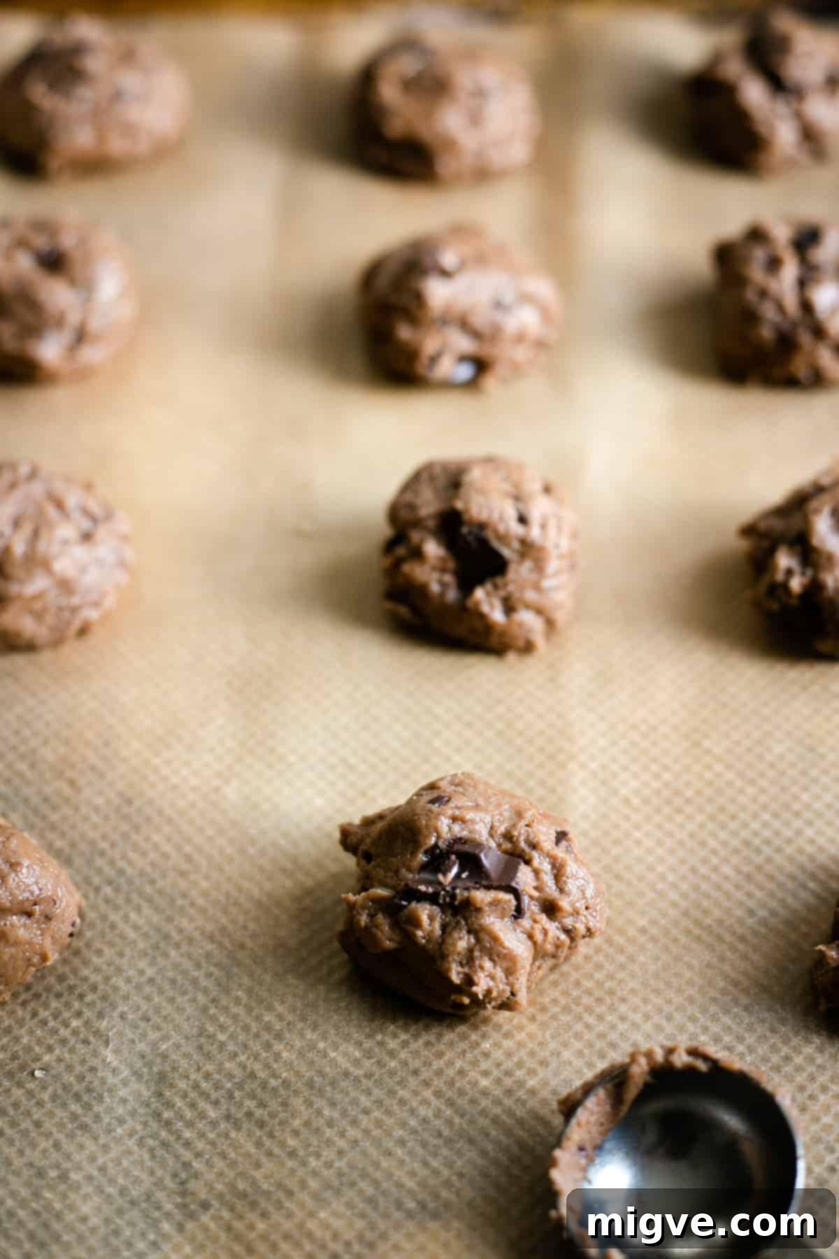 Decadent Chocolate and Salted Caramel Treats 5 A straight-ahead shot captures perfectly portioned, raw chocolate cookie dough balls neatly arranged on a baking tray, poised for their transformation in the oven.