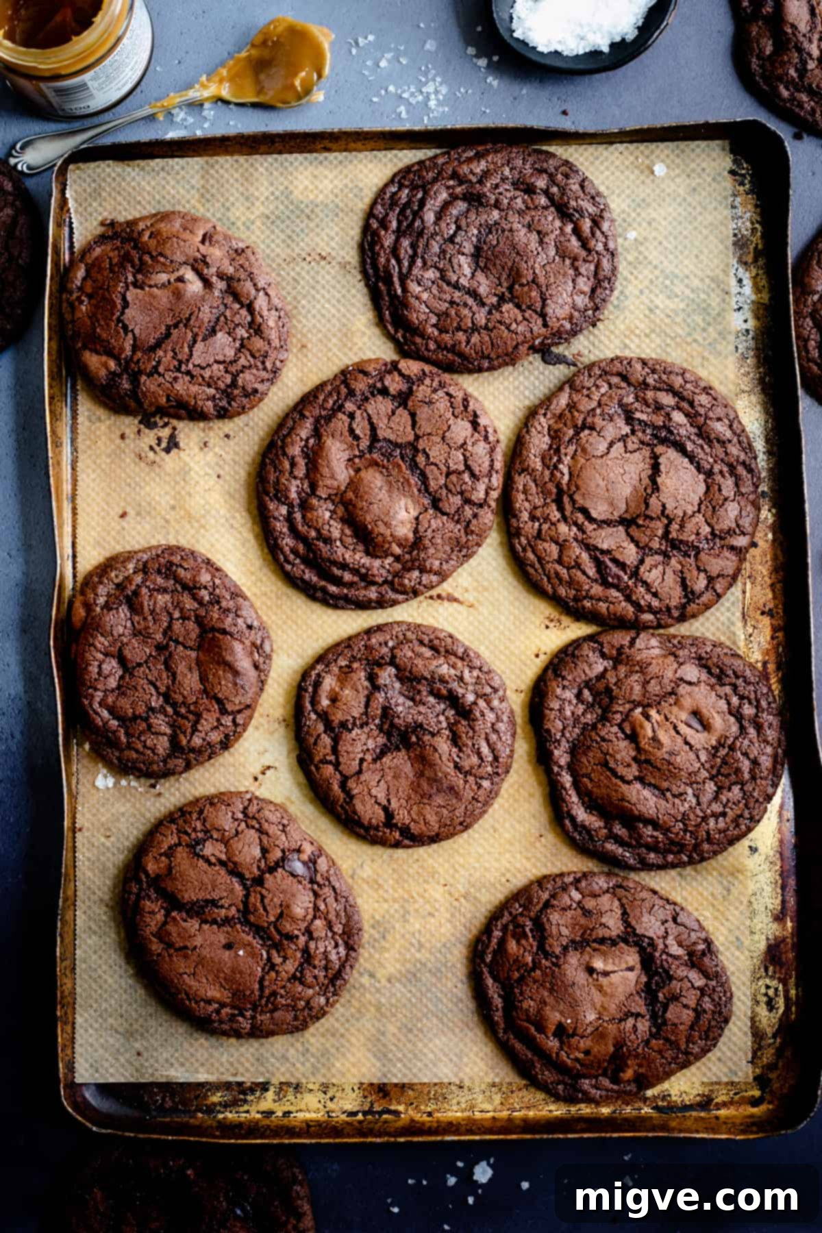 Decadent Chocolate and Salted Caramel Treats 7 An overhead shot showcasing a rustic, old baking tray filled with a fresh batch of richly colored chocolate cookies, highlighting their perfectly baked texture.