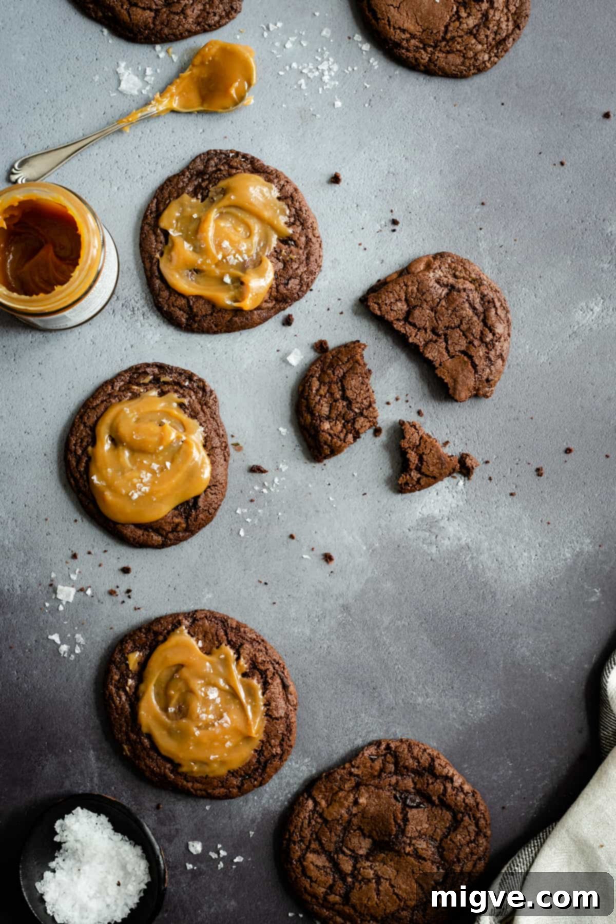 Decadent Chocolate and Salted Caramel Treats 8 An overhead shot of freshly baked chocolate salted caramel cookies beautifully arranged with a small, inviting jar of caramel and a sprinkle of sea salt on the side.