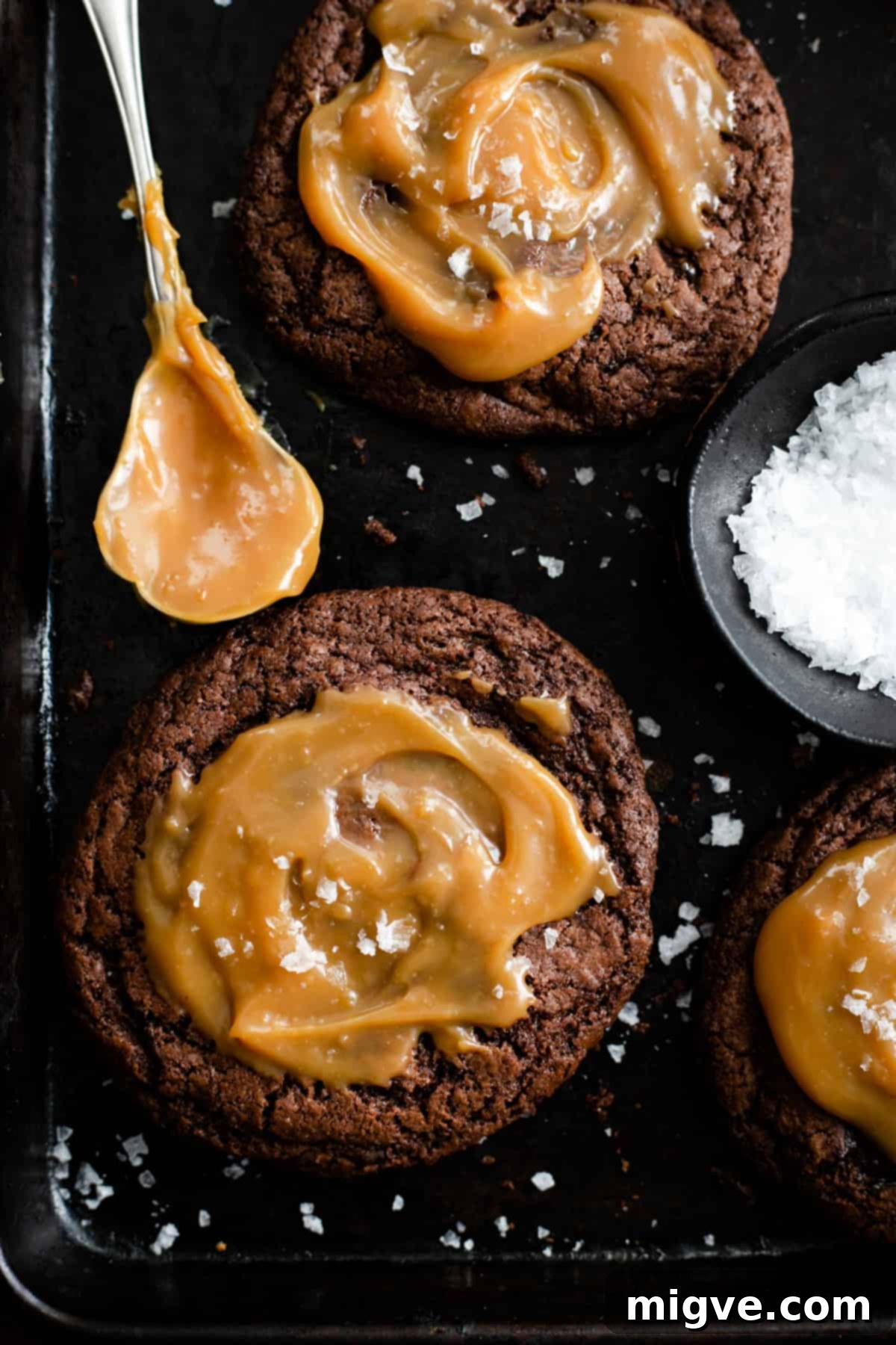 Decadent Chocolate and Salted Caramel Treats 9 A close-up shot of a trio of irresistible chocolate salted caramel cookies resting on a baking tray, showcasing their rich texture and tempting caramel drizzle.