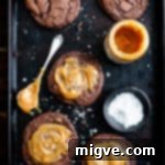 Decadent Chocolate and Salted Caramel Treats 10 Overhead shot of five big chocolate salted caramel cookies on a baking tray with small bowl of sea salt and small jar of caramel, enticing viewers to indulge.
