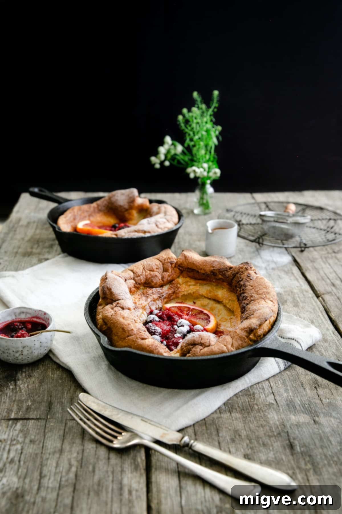 Berry Burst Dutch Delight 2 Two small skillets with mixed berry Dutch babies on a wooden table, fresh for breakfast