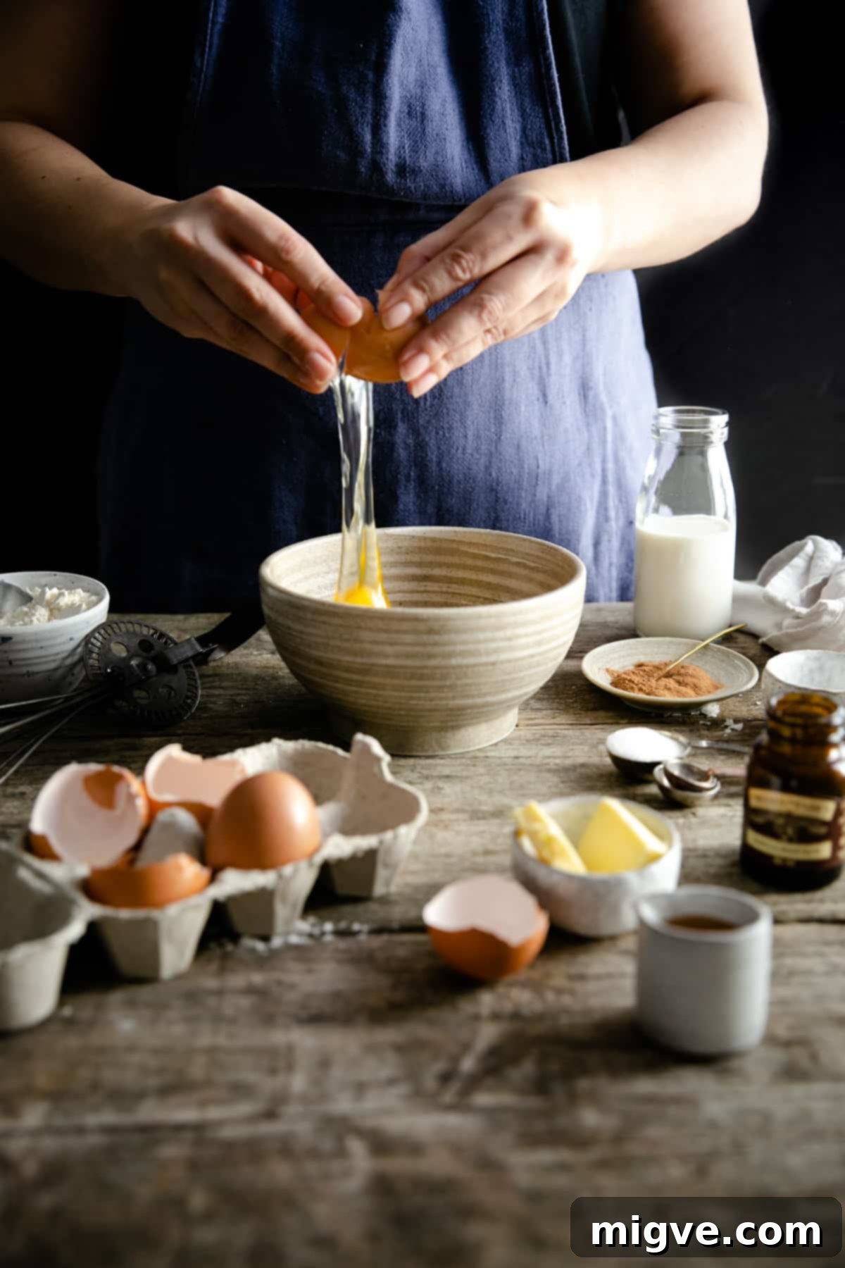 Berry Burst Dutch Delight 5 A person cracking an egg into a small bowl while preparing Dutch baby pancake batter