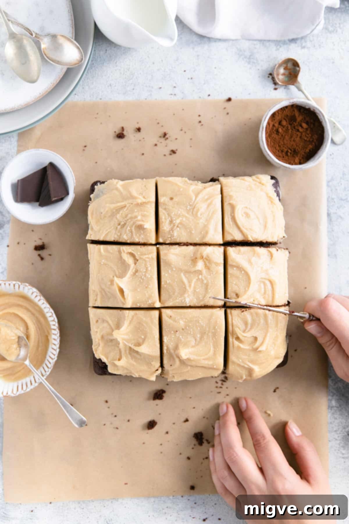 overhead view of a person slicing chocolate brownies with peanut butter frosting
