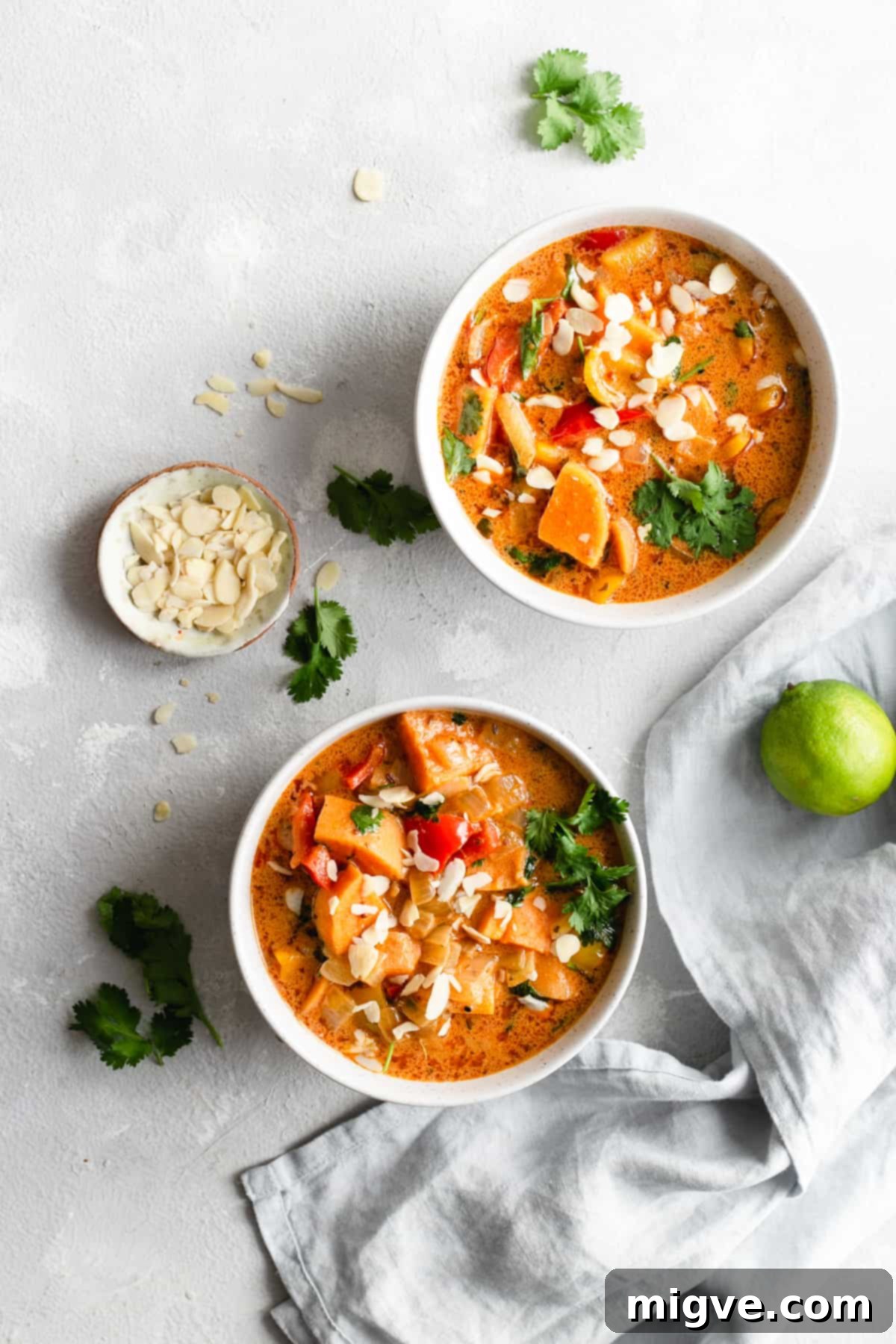 Golden Coconut Sweet Potato Curry 6 overhead shot of two small bowls with sweet potato curry with some toasted almonds and lime on side