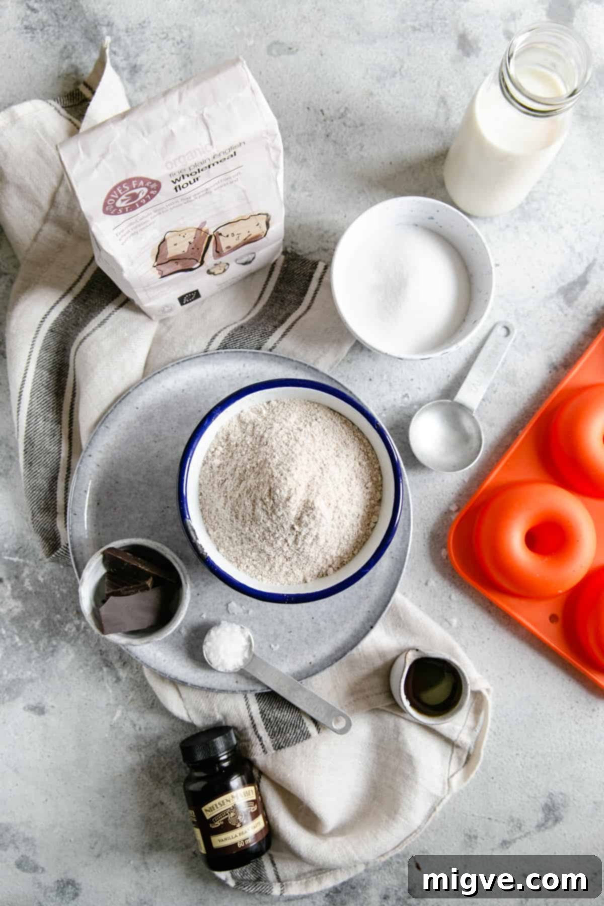 overhead shot of some of the ingredients for baked doughnuts; flour, chocolate, maple syrup, milk