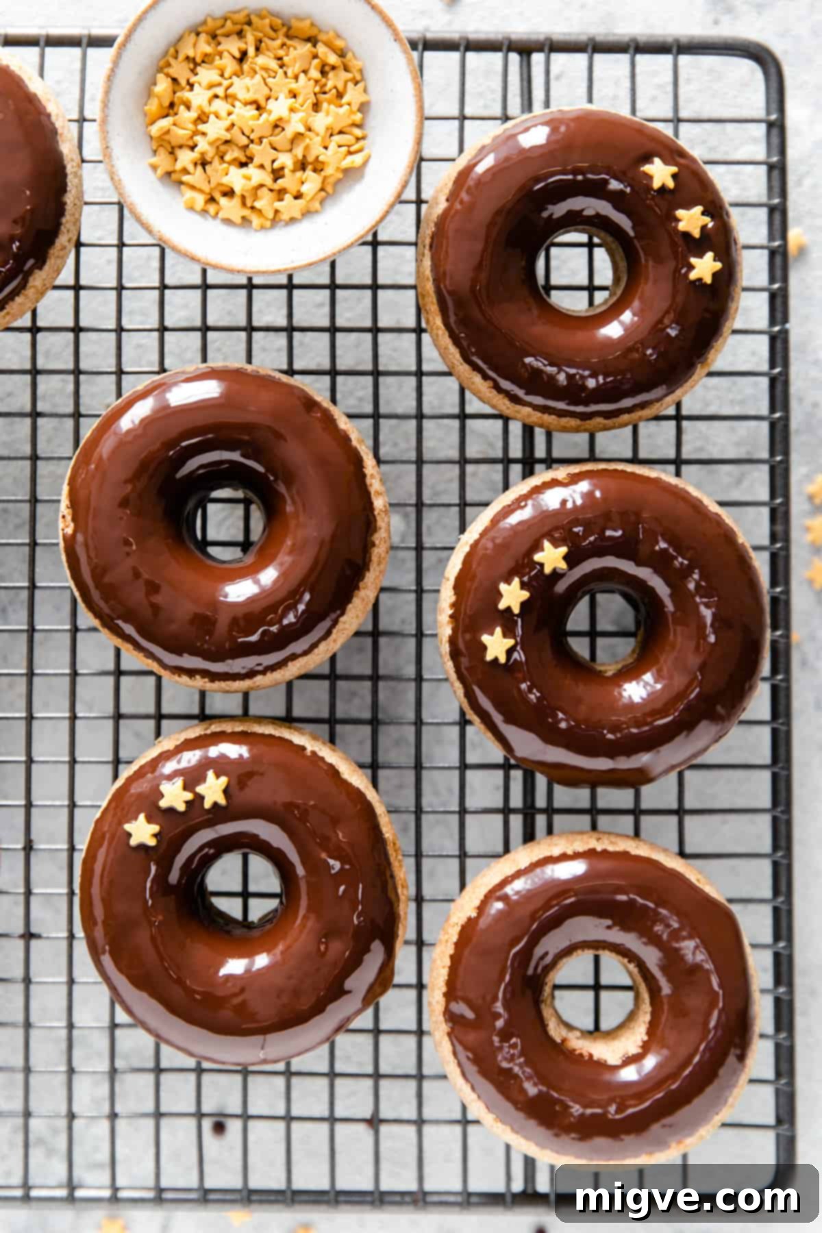 overhead shot of baked doughnuts dipped in chocolate glaze decorated with small star-shaped sprinkles