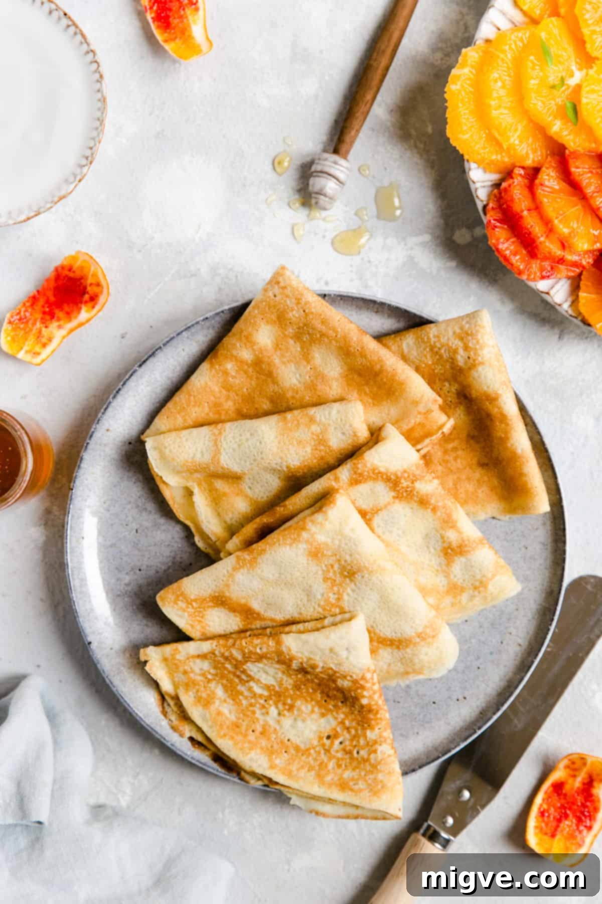 Overhead shot of a plate with three thin crepes gracefully folded into neat triangles, ready to be served