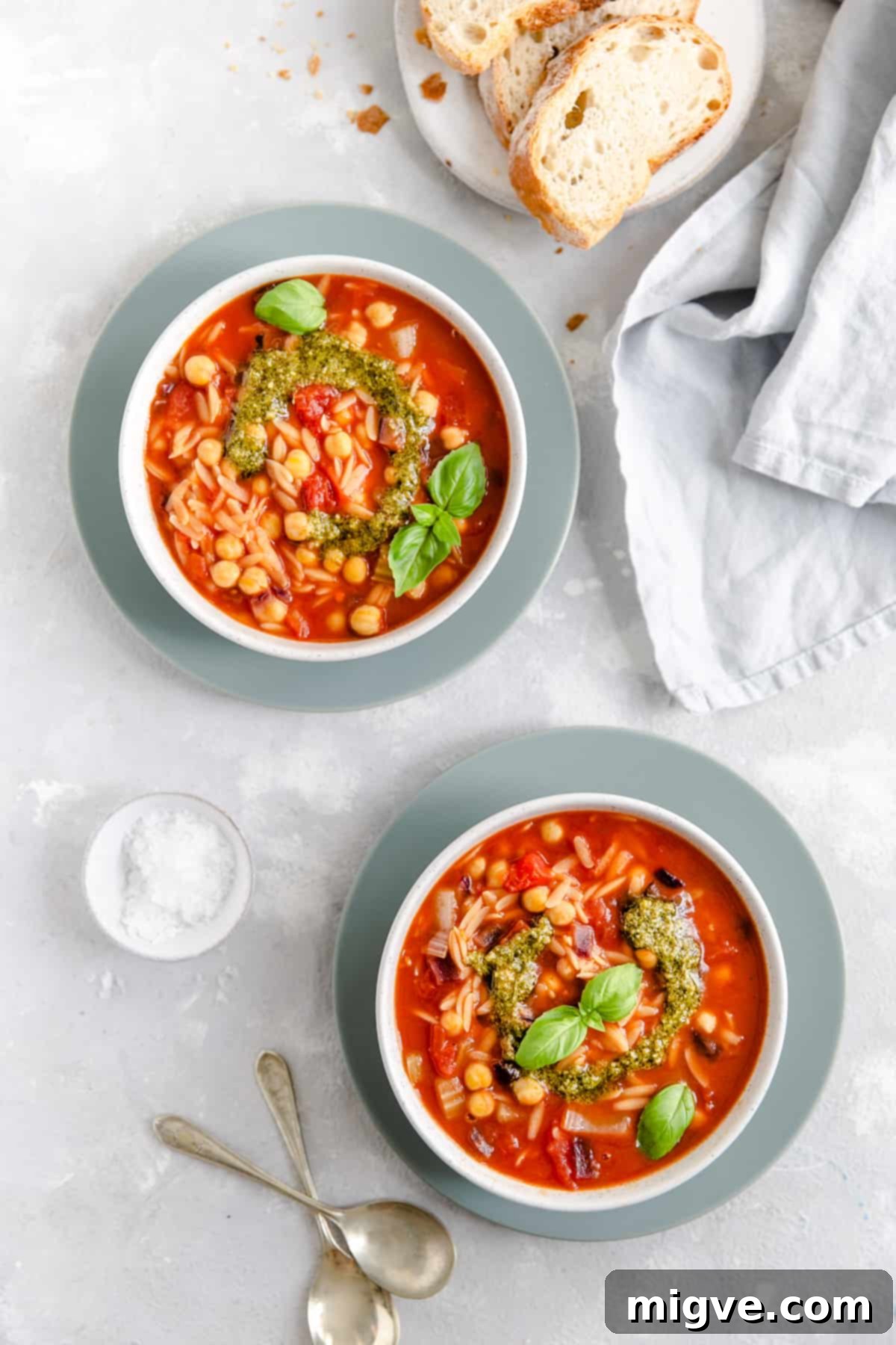 Overhead shot of two beautifully garnished bowls of Orzo and Tomato Soup, ready to be served