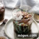 A small glass filled with vegan chocolate pudding and topped with whipped coconut cream