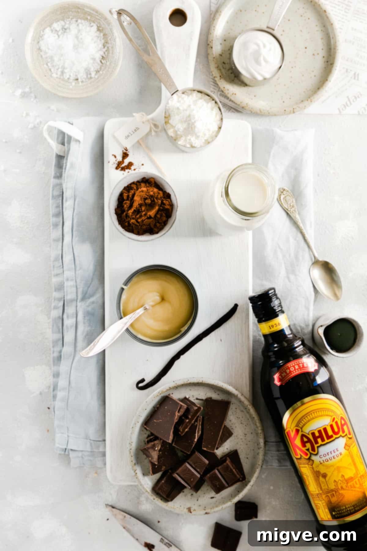 Overhead shot of the ingredients for the vegan chocolate pudding: dark chocolate, coffee liquor, condensed coconut milk, almond milk, cocoa, cornflour, salt and vanilla