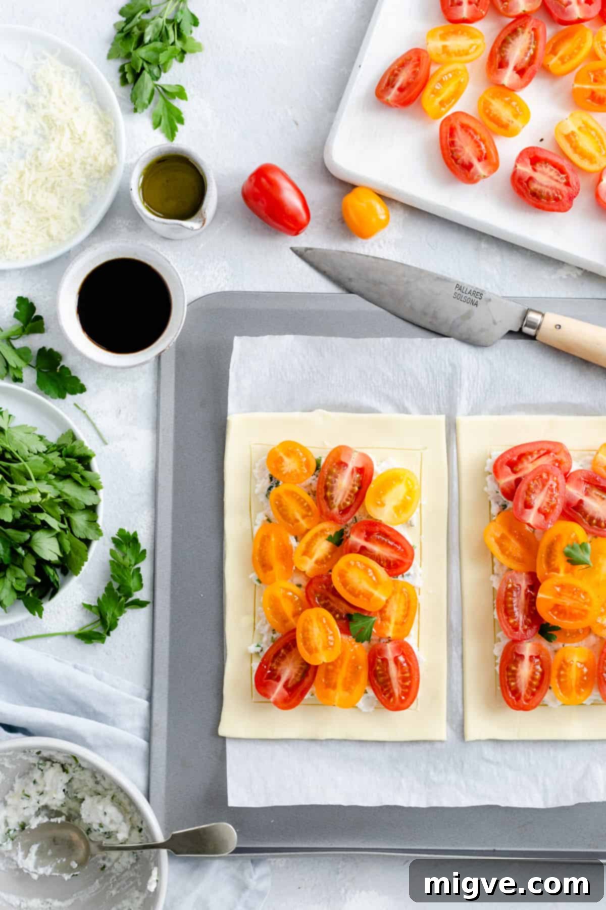 Vibrant Tomato & Savory Cheese Tartlets 6 Overhead shot of unbaked mixed tomato and cheese tartlets, generously topped with colorful tomatoes and cheese, arranged on a baking tray.
