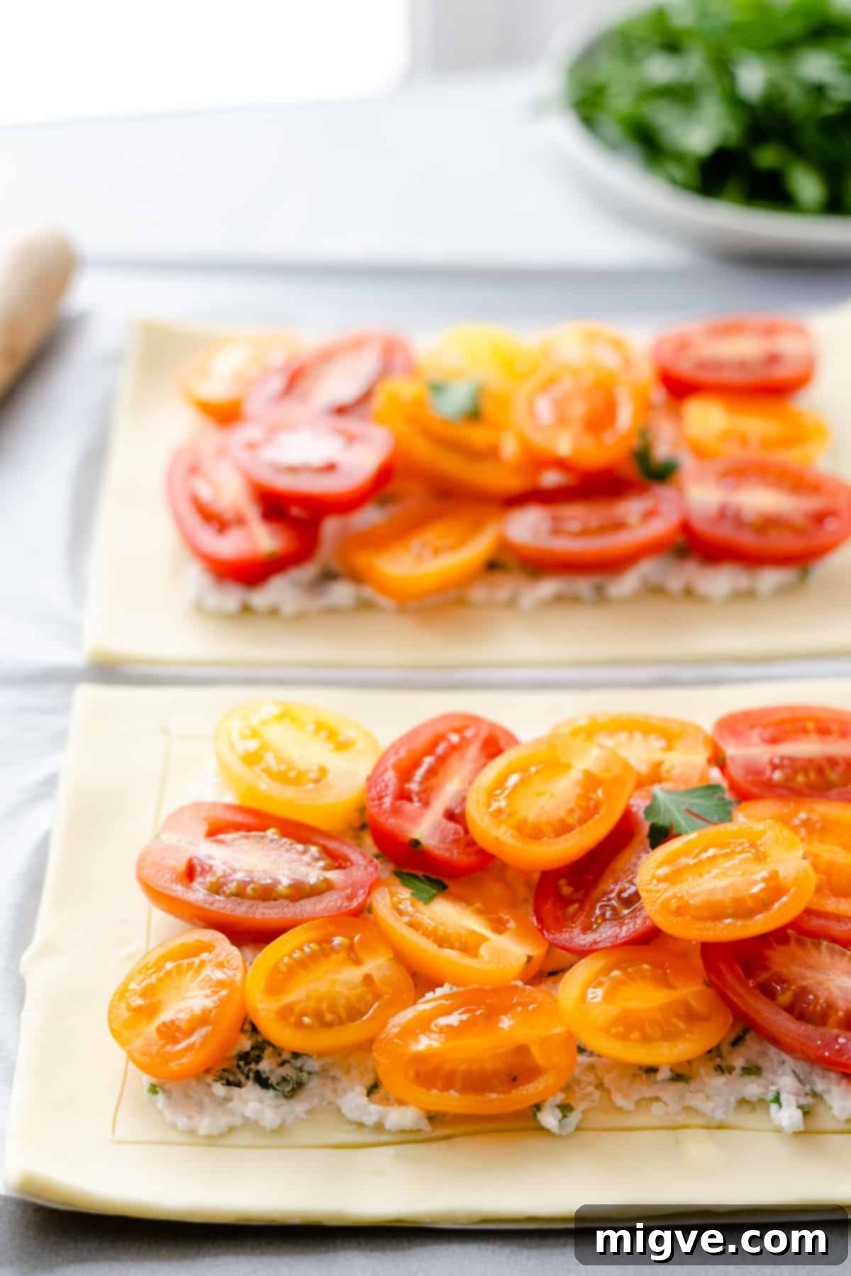 Vibrant Tomato & Savory Cheese Tartlets 7 Side shot of the unbaked mixed tomato and cheese tartlets on a baking tray, showcasing their vibrant toppings and neatly scored pastry edges.
