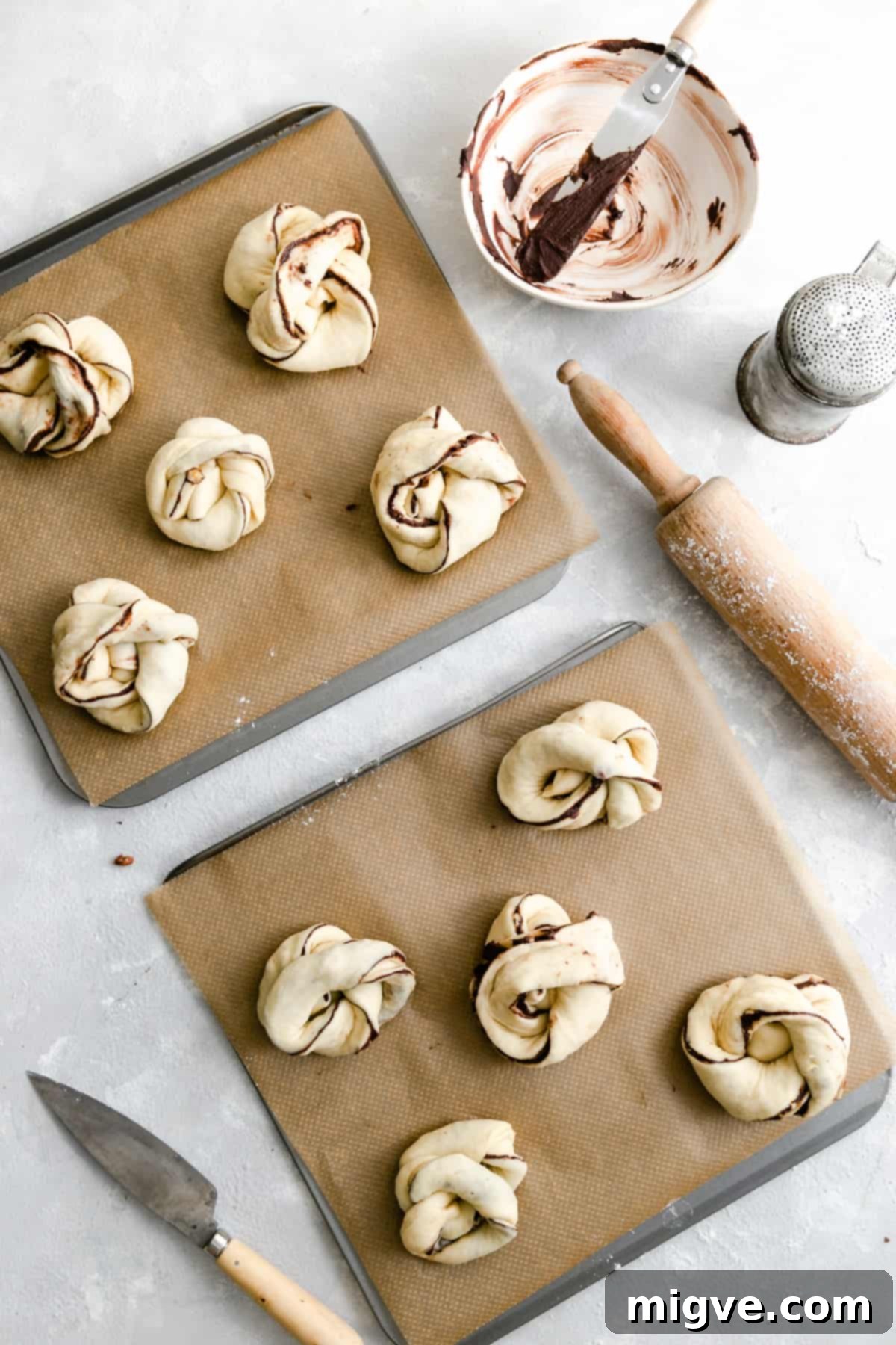 Swirled Chocolate Hazelnut Babka Buns 8 Overhead shot of two baking sheets filled with unbaked chocolate hazelnut babka buns, perfectly risen and ready for the oven.