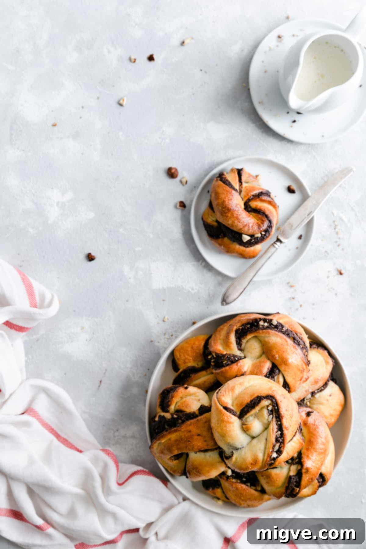 Swirled Chocolate Hazelnut Babka Buns 10 Overhead shot of a large plate brimming with chocolate hazelnut babka buns, with a small plate holding a single bun nearby, illustrating the generous yield of the recipe.