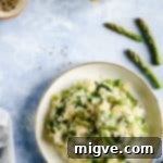 Overhead shot of a single bowl with wild garlic and asparagus risotto with few asparagus tips and lemons on side