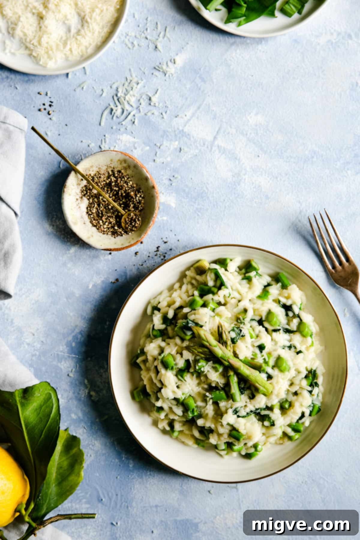 Overhead shot of a bowl with wild garlic and asparagus risotto with small side dish with black pepper
