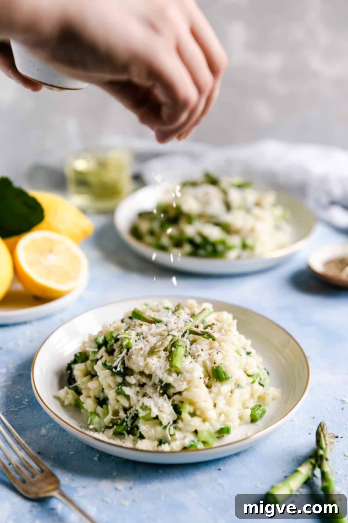 straight ahead shot of a person sprinkling cheese into a bowl of wild garlic and asparagus risotto
