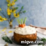 Vegan carrot cake topped with cream cheese frosting and some carrot tops