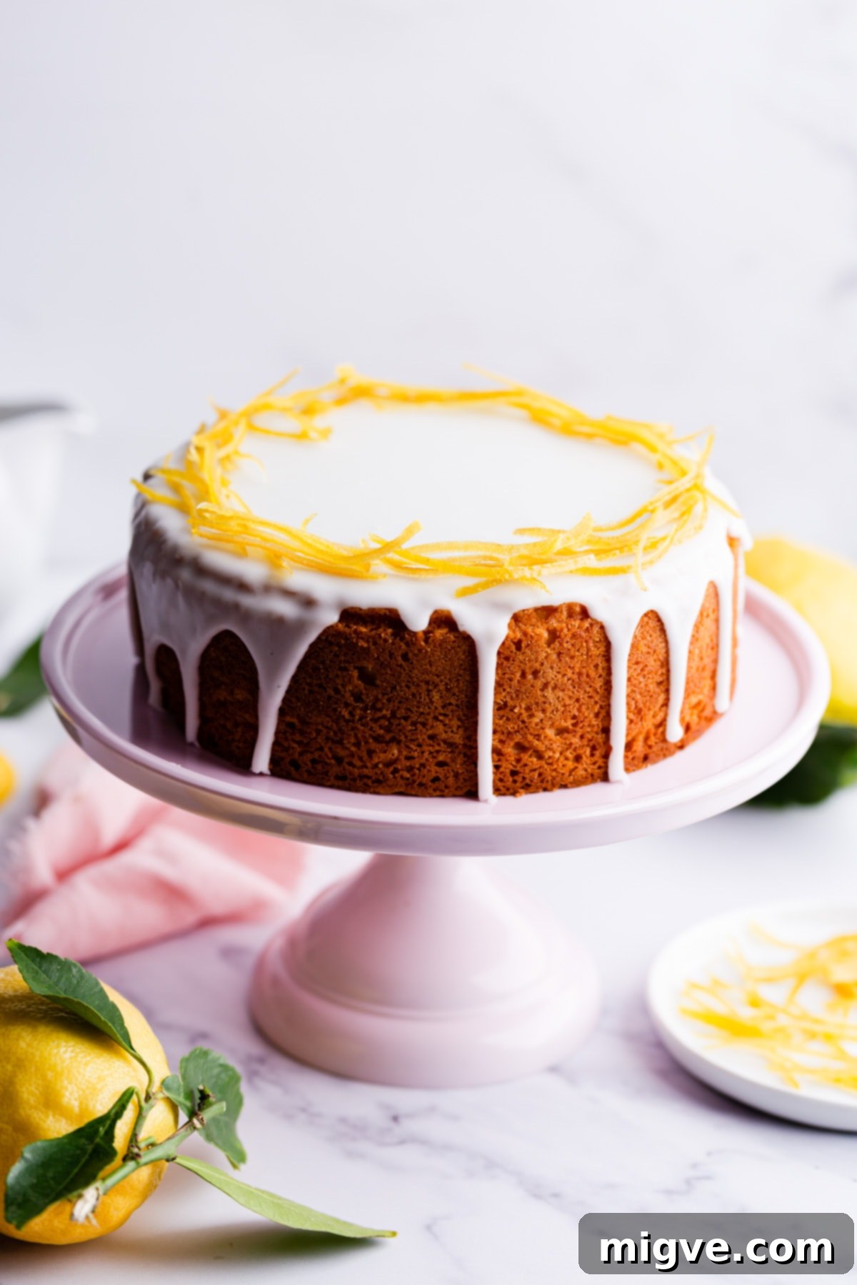 A beautifully decorated citrus sponge cake with white icing gently dripping from its sides, evoking freshness and zest.