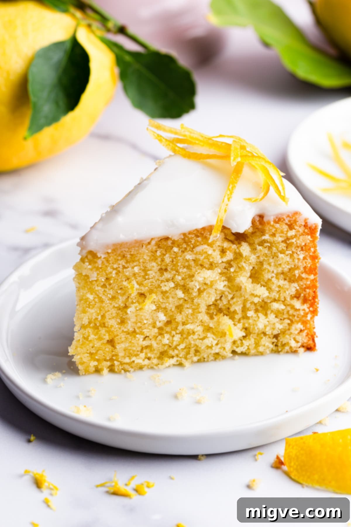 A single, perfectly cut slice of zesty lemon cake presented on a small plate.